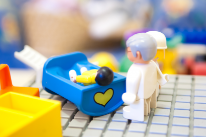 Des playmobils représentant un enfant couché sur un lit et deux adultes à son chevet.