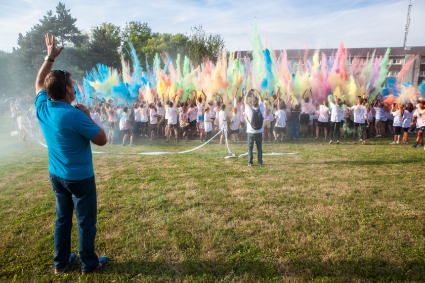 Un grand groupe d'étudiants lance en l'air des nuages de poudre colorée.