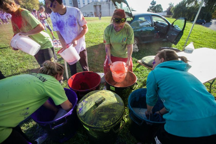 Des étudiants en tee-shirt vert préparent des seaux de poudre colorée
