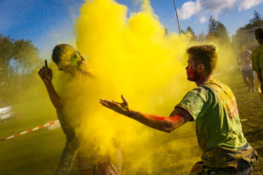 Un jeune homme lance un nuage de poudre jaune sur un coureur.