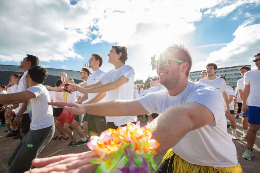 Des étudiants accroupis et souriants avec guirlandes et lunettes.