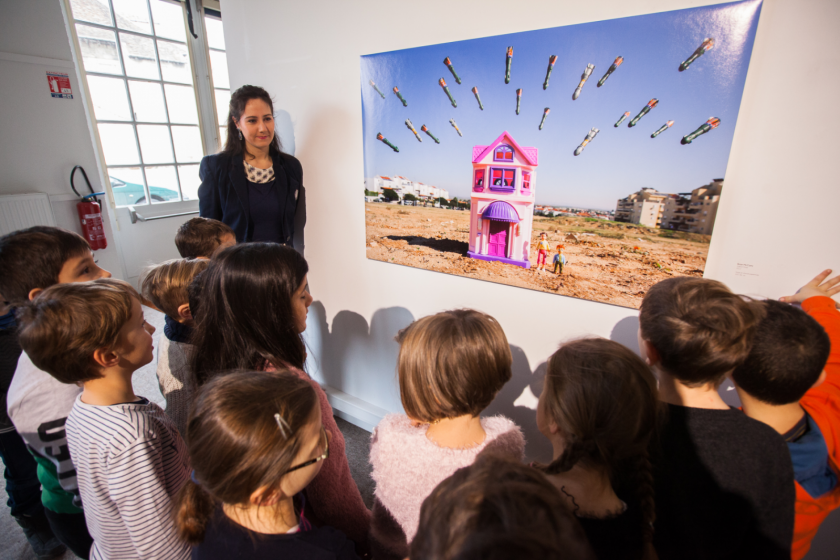 Une jeune femme et un groupe d'enfants devant une photo de Brian Mc Carty