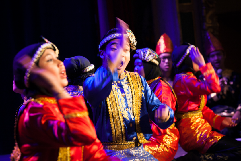Danse traditionnelle en costume. Un homme fait de grands gestes en souriant.