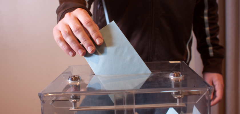 Une main dépose une enveloppe dans une urne