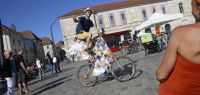 Place de la révolution à Besançon : un jeune homme perché sur un vélo très haut fait signe au photographe.