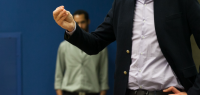 Un étudiant en costume parle devant un public