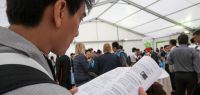 Un homme asiatique de dos feuillette un document scientifique. Beaucoup de monde debout en arrière-plan.