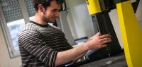 Un étudiant tient un appareil qui ressemble à une fraiseuse.