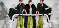 Scène de théâtre : trois jeunes hommes discutent autour d'une échelle.