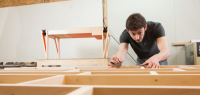 Samuel Hélias penché sur une réalisation en bois dans son atelier.