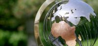 Un globe terrestre transprent sur fond de végétation.