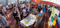 Vue intérieure de la grande halle de l'U-sports remplie d'étudiants et de stands.