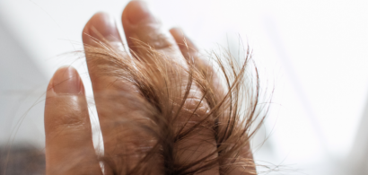 Des cheveux qui passent entre les doigts d'une main.