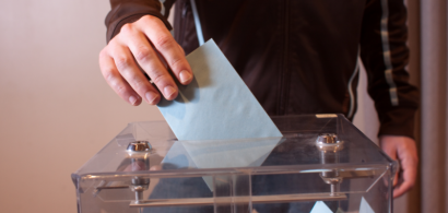 Une main dépose une enveloppe dans une urne