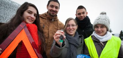 Les étudiants organisateurs posent avec un triangle de signalisation, des clés de voiture et un gilet jaune fluo