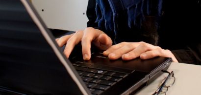 Un jeune homme devant un clavier d'ordinateur.