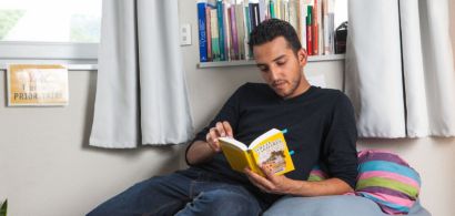 Un étudiant en train de lire un livre sur un lit.