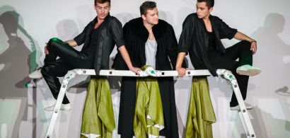 Scène de théâtre : trois jeunes hommes discutent autour d'une échelle.