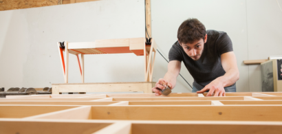 Samuel Hélias penché sur une réalisation en bois dans son atelier.