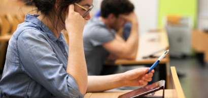 Une jeune femme assise en train de réfléchir devant une tablette.