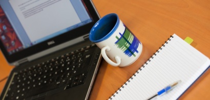 Un ordinateur portable, un mug et un cahier