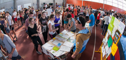 Vue intérieure de la grande halle de l'U-sports remplie d'étudiants et de stands.