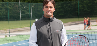 Vincent Peseux sur un court de tennis avec une raquette. Des enfants en arrière plan