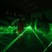 Des silhouettes se déplacent entre des lasers dans le noir.