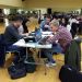 Des groupes d'étudiants en train de travailler dans une grande salle.