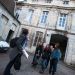 Une enseignante qui tient des documents parle à un groupe dans la cour de la faculté des lettres.