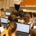 Marion Bendinelli donne un cours devant des étudianst en amhithéâtre dont beaucoup ont des ordinateurs ouverts.