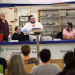 Plusieurs conférenciers et des acteurs du théâtre universitaire derrière la banque d'accueil d'une bibliothèque.