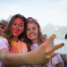 Deux étudiantes couvertes de poudre colorée font un selfie.