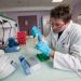Un doctorant assis fait un prélèvement à l'aide d'une pipette.
