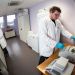 Un chercheur et un doctorant, tous deux en blouses blanches, manipulent des échantillons, chacun à un poste de travail différent.