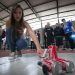 Une collégienne accroupie présente son robot fait de canettes de coca-cola.