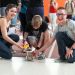 Trois collégiens rient accroupisd errirèe leur robot.
