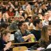 En amphithéâtre. Les étudiants, nombreux, sourient ou rient.
