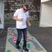 Un jeune homme portant des lunettes semblables à un masque de plongée en train de marcher sur un tapis où est imprimée une route et où sont disposés des cônes de signalisation.