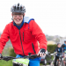 Un jeune homme en veste rouge portant un casque tout sourire sur un VTT