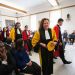 Plusieurs personnes en toges de différentes couleurs font leur entrée dans la salle.