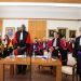 Quatre personnes en toge se tiennent debout au premier plan.