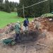 Deux hommes sur un chantier de fouilles. Sur une zone circulaire la terre prend une couleur noire.