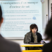 Une feme assise à un bureau en train de parler, derrière elle un texte projeté sur un écran avec pour titre "conséquences d'un manque d'estime de soi"