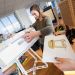 Deux étudiantes travaillent sur une maquette de meuble dont on voit le dessin au premier plan.