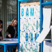 Un meuble mobile, des affiches BAM ! et des personnes souriantes autour du plan de travail.