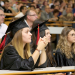 Deux jeunes filles avec toques et chapeaux de diplômés dans un amphithéâtre.
