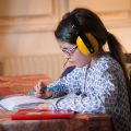 Une fillette fait ses devoirs avec un casque anti-bruit sur les oreilles.