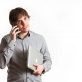 Un jeune homme en train de téléphoner et tenant un ordinateur portable