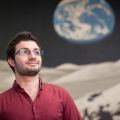 Photo du doctorant avec un fond représentant l&#039;espace et une planète derrière lui